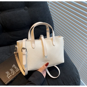 Detail of cream faux crocodile texture handbag with adjustable strap and logo