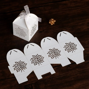 Detail of white laser-cut Tree of Life candy box with a satin bow and unfolded flat piece