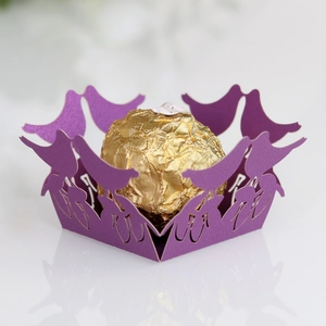 Detail of laser cut purple candy box with bird pattern holding a chocolate truffle