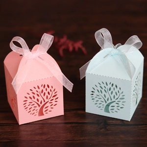 Detail of tree laser-cut hollow gift boxes with organza ribbons on wood surface
