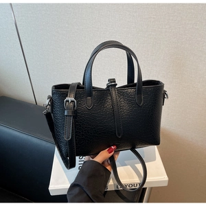 Close-up of black crocodile pattern faux leather handbag with silver metal hardware