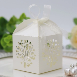 Macro detail of laser-cut tree design on white candy box with ribbon for party