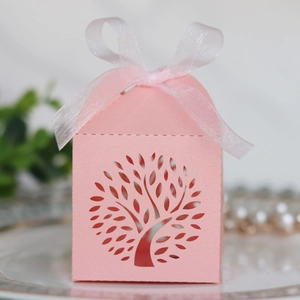 Detail of pink laser-cut tree gift box with white ribbon bow and house-shaped design