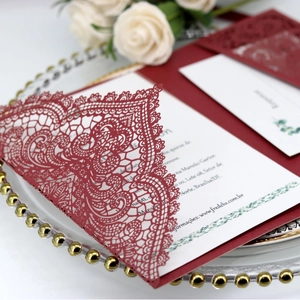 Elegant burgundy laser-cut lace wedding invitation with a white inner card on a silver tray