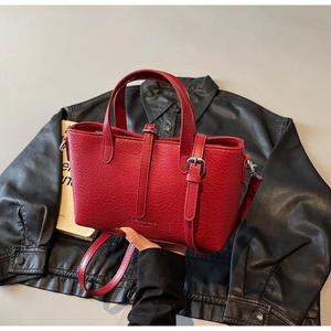 Close-up of bright red crocodile pattern leather handbag with silver metal buckles