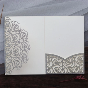 Detailed laser-cut silver glitter rose pattern on cream paper wedding invitation card