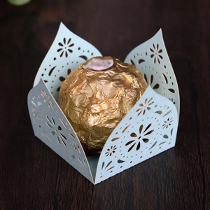Detail of light blue laser-cut candy holder with floral pattern on wood background