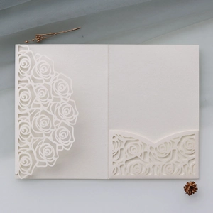 Detailed laser-cut pearlescent white wedding invitation with elegant rose pattern