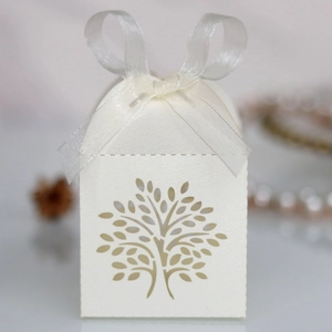 Detailed laser-cut tree design on white paper favor box with elegant organza ribbon bow