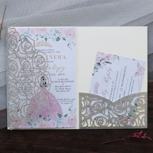 Detail of silver glitter laser-cut rose invitation with pink dress cards on wood background