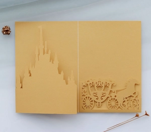 Detailed laser-cut gold castle and carriage silhouette on mustard art paper invitation