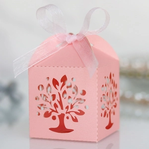 Detailed laser-cut tree of life pattern on pink wedding candy box with ribbon