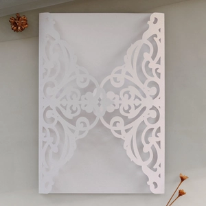 Detail of laser-cut white pearlescent paper invitation with intricate floral hollow pattern