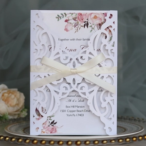 Detail of laser-cut purple wedding invitation with ribbon and floral inner card