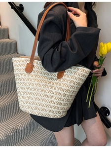 Grande borsa tote in paglia intrecciata con cinturini in pelle marrone indossata da modella