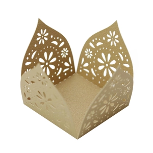 Detailed close-up of champagne gold laser-cut floral pattern on wedding favor boxes