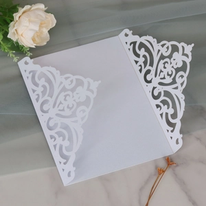 Macro detail of laser-cut floral pattern on elegant white wedding invitation cover