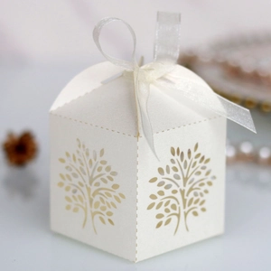 Macro detail of laser-cut tree design on white paper gift box with organza ribbon bow
