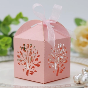 Close-up of pink laser-cut tree favor box with a delicate sheer ribbon and hollow texture