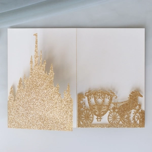 Detail der lasergeschnittenen Hochzeitseinladung mit goldenem Glitzerschloss und Kutsche