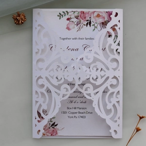 Detail of laser-cut wedding invitation with elegant vine patterns and floral insert