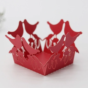 Close-up of red laser-cut candy box featuring intricate hollow bird designs for weddings