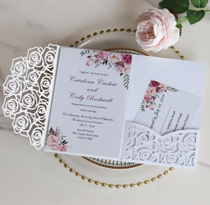 Laser-cut rose pattern wedding invitation with floral insert card on marble surface