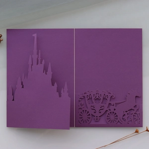 Detailed laser-cut fairy tale castle and horse carriage on purple wedding invitation
