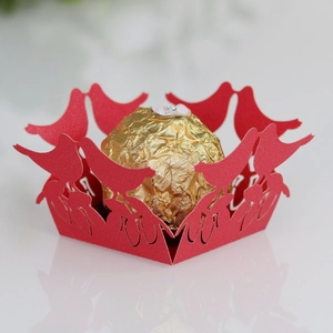 Macro detail of red laser-cut paper bird candy box with hollow lace design for weddings