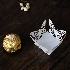 Detailed laser-cut white butterfly candy box on wooden background for weddings