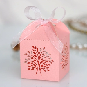 Detail of pink laser-cut tree gift box with elegant white ribbon bow for wedding favors