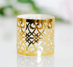 Close-up of golden hollowed-out napkin ring with elegant floral and heart patterns