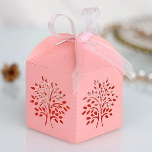 Detail of pink laser-cut tree candy box with elegant ribbon for wedding party gift