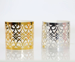 Detail of laser-cut rose gold and silver napkin rings with intricate floral patterns