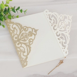 Détail de l'invitation de mariage découpée au laser en paillettes dorées et ivoire