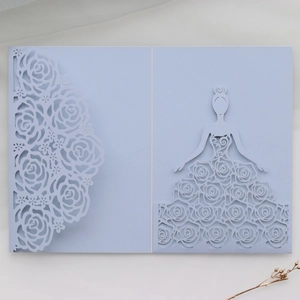 Macro shot of light blue laser-cut wedding invitation featuring rose patterns and a girl motif