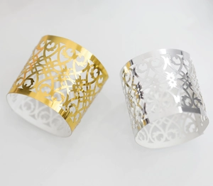 Detail of laser-cut rose gold and silver napkin rings with intricate floral patterns