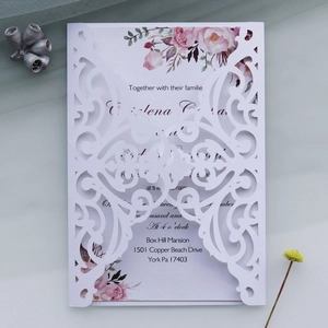 Macro view of white laser cut floral wedding invitation with delicate flower inner card