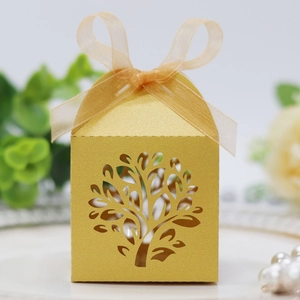 Close-up of golden laser-cut gift box with Tree of Life pattern and organza ribbon