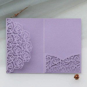 Detail of purple laser-cut rose hollow invitation cover on elegant grey backdrop