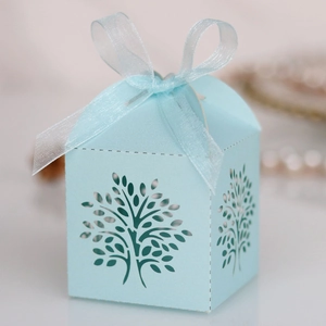Detailed close-up of light blue laser-cut tree gift box with ribbon bow and paper texture