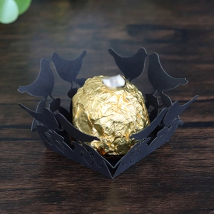 Laser-cut black hollow bird design favor box base with a gold foil wrapped chocolate