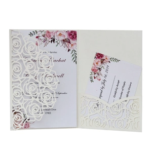 Close-up of laser-cut ivory rose wedding invitation with watercolor floral inner cards