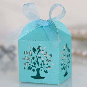 Close-up of laser-cut tree design on light blue wedding favor box with organza ribbon