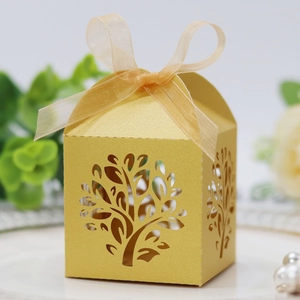 Detail of laser-cut tree design on gold wedding favor box with ribbon and elegant decor