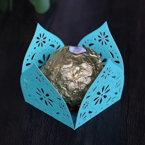 Detail of blue laser-cut candy box with floral pattern and golden chocolate inside