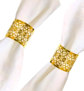 Close-up of gold hollow-out napkin rings with intricate patterns on white napkins