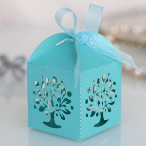 Macro detail of laser-cut tree design on light blue gift box with sheer ribbon bow