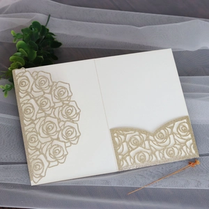 Detail of laser-cut wedding invitation with gold glitter rose pattern on cream cardstock