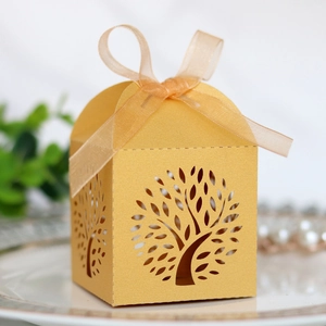 Detail of laser-cut tree of life candy box in gold pearlescent paper with organza ribbon